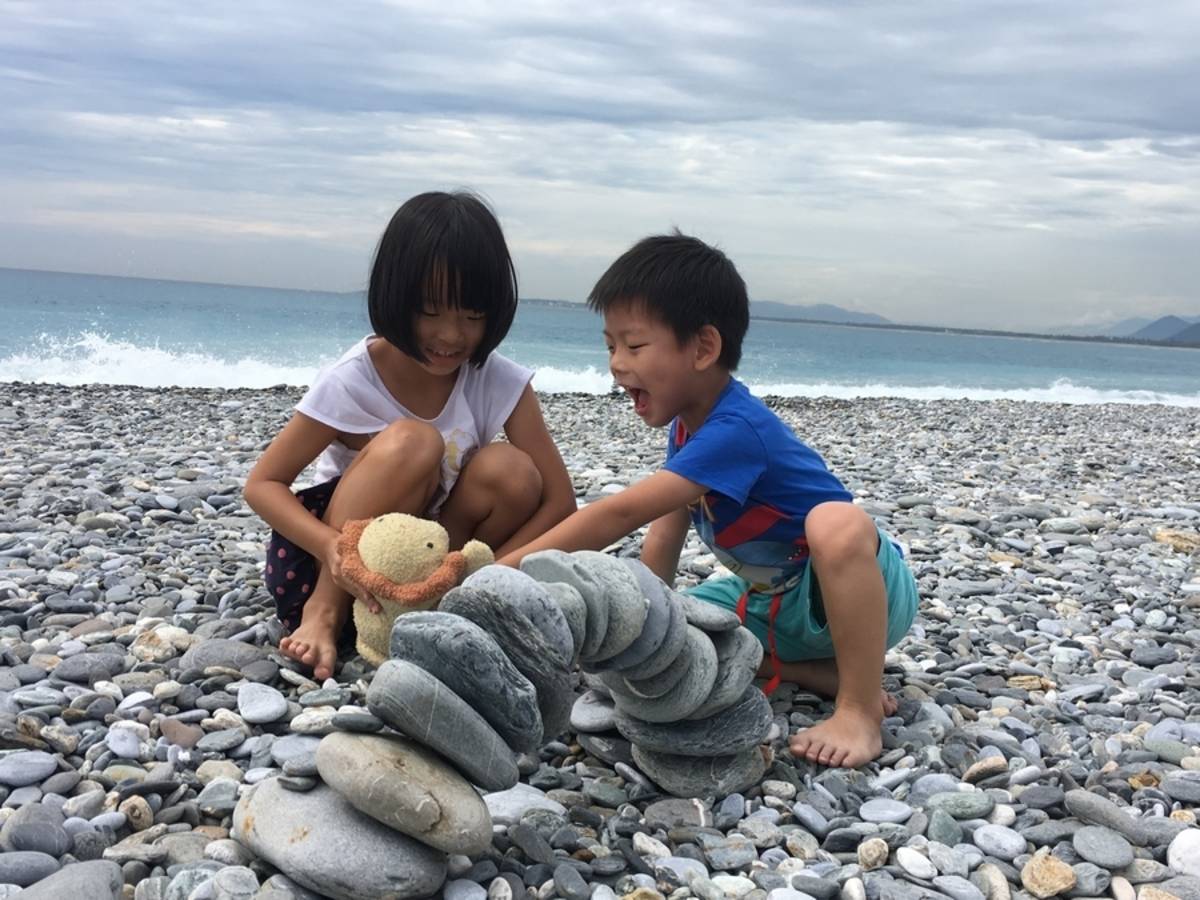 孩子們耐心的堆疊著石頭，想要搭建一座拱橋。