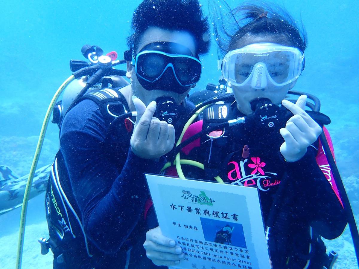 綠島鄉公館國小的小朋友參與海底畢業典禮，從高志翔校長手中取得畢業證書，開心的比出愛心的手勢。
