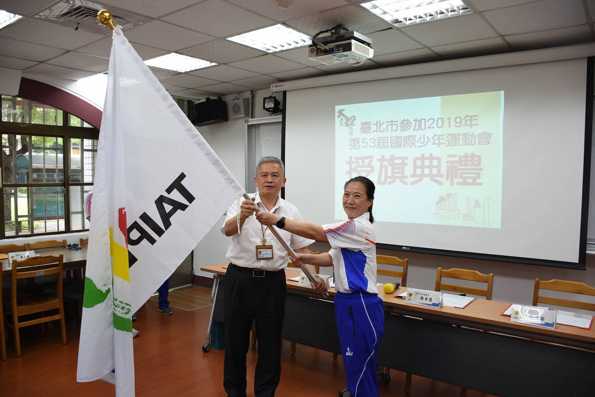  臺北市教育局副局長洪哲義授旗勉勵選手們奪得佳績
