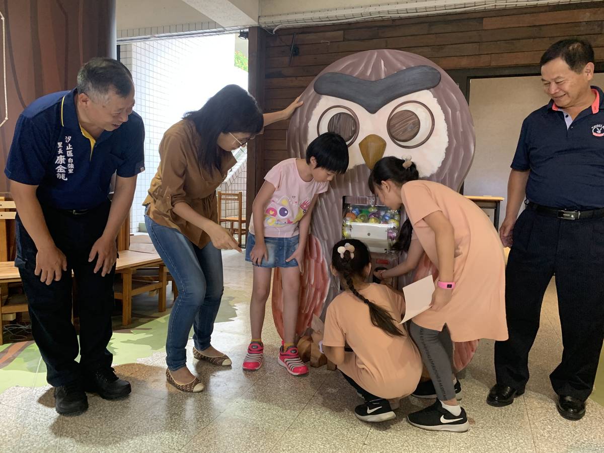 小一新生轉動大型貓頭鷹博士扭蛋機，滑出各式各樣的動物木雕鑰匙圈，送給阿公阿媽作為祖父母節的幸運禮物