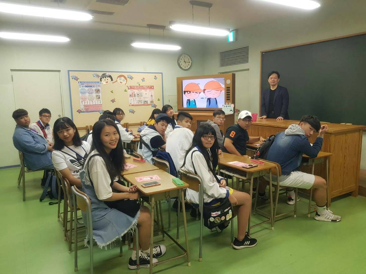 林裕豐校長率團前往日本姊妹校交流，參訪日本靜岡小丸子故事館，在卡通櫻桃小丸子上課的教室內，與永豐高中同學們合影。(林裕豐提供)