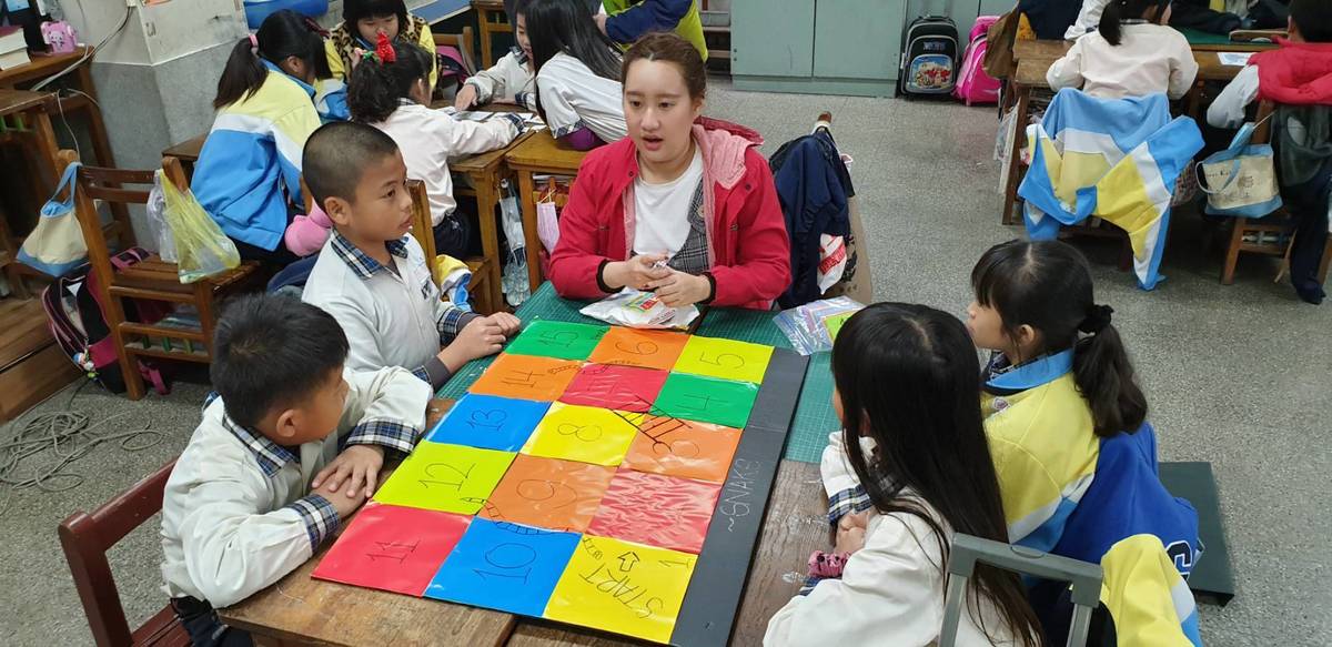 大葉大學英語系碩士班的印尼學生翁淑妮(中)用蛇梯棋遊戲教小朋友英語