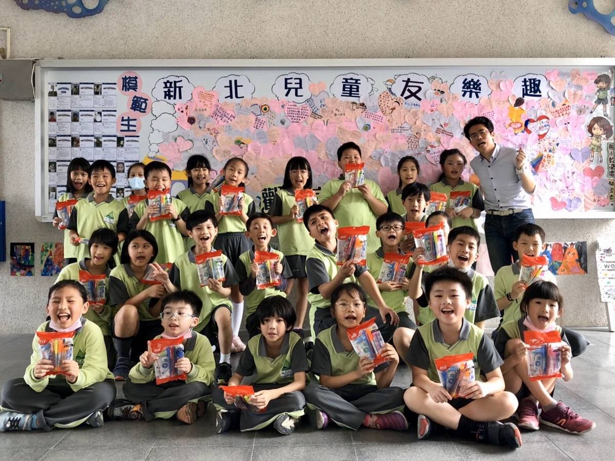 學生們開心拿著自己的兒童節禮物在「達觀兒童宜起圓夢牆」前合影