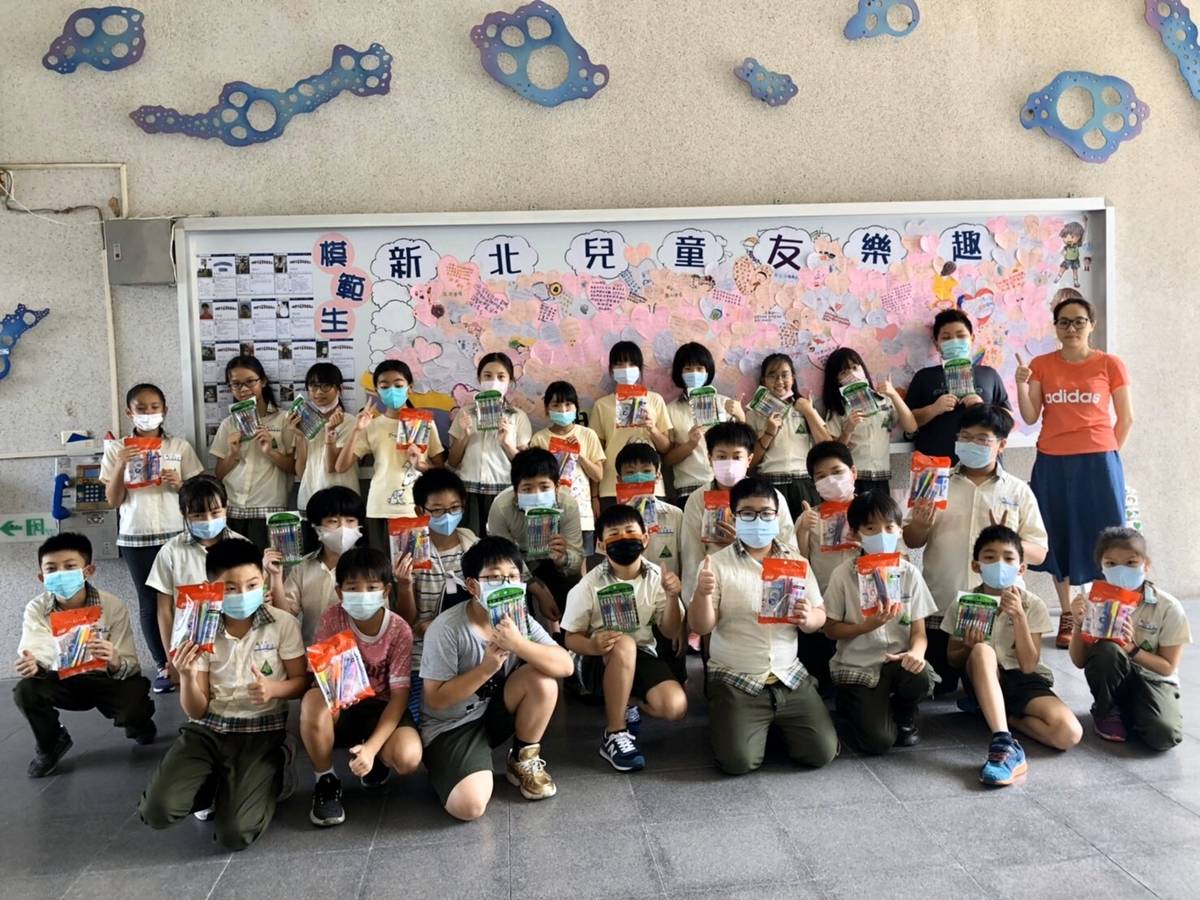 學生們開心拿著自己的兒童節禮物在「達觀兒童宜起圓夢牆」前合影