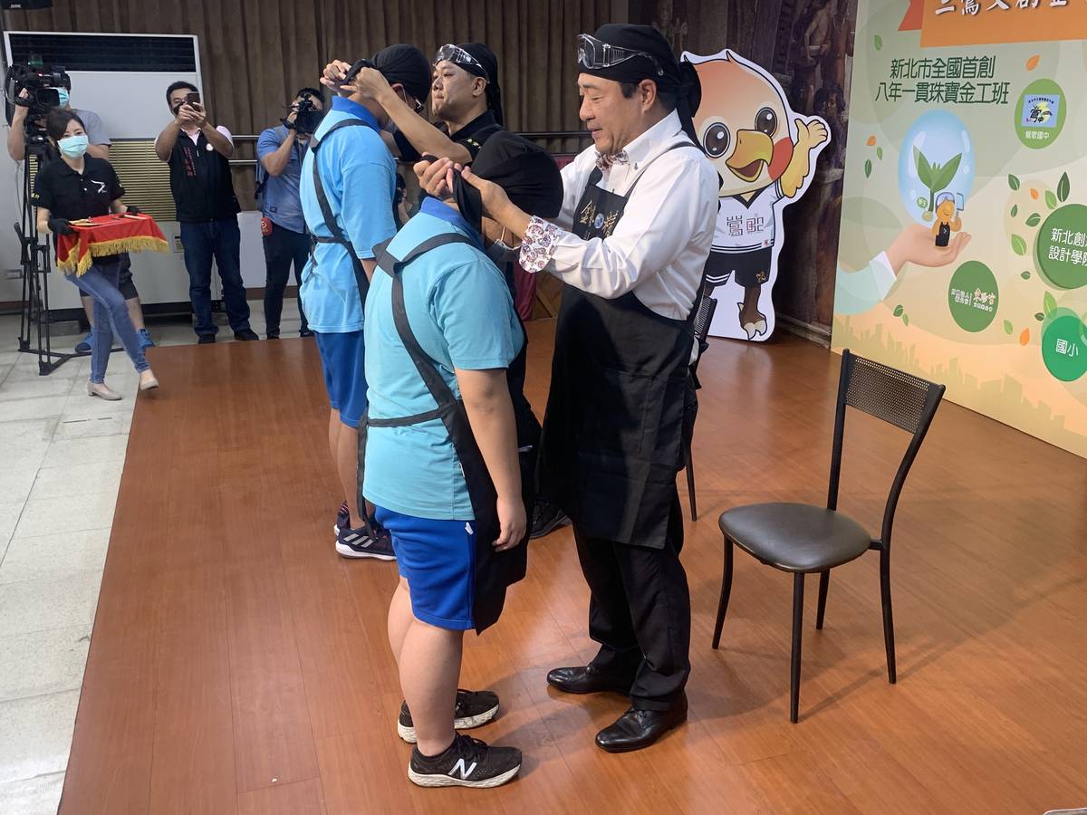 由無償捐贈課程所需材料的東龍珠鑽石集團執行長張芳榮(右)替學生綁上職人頭巾。