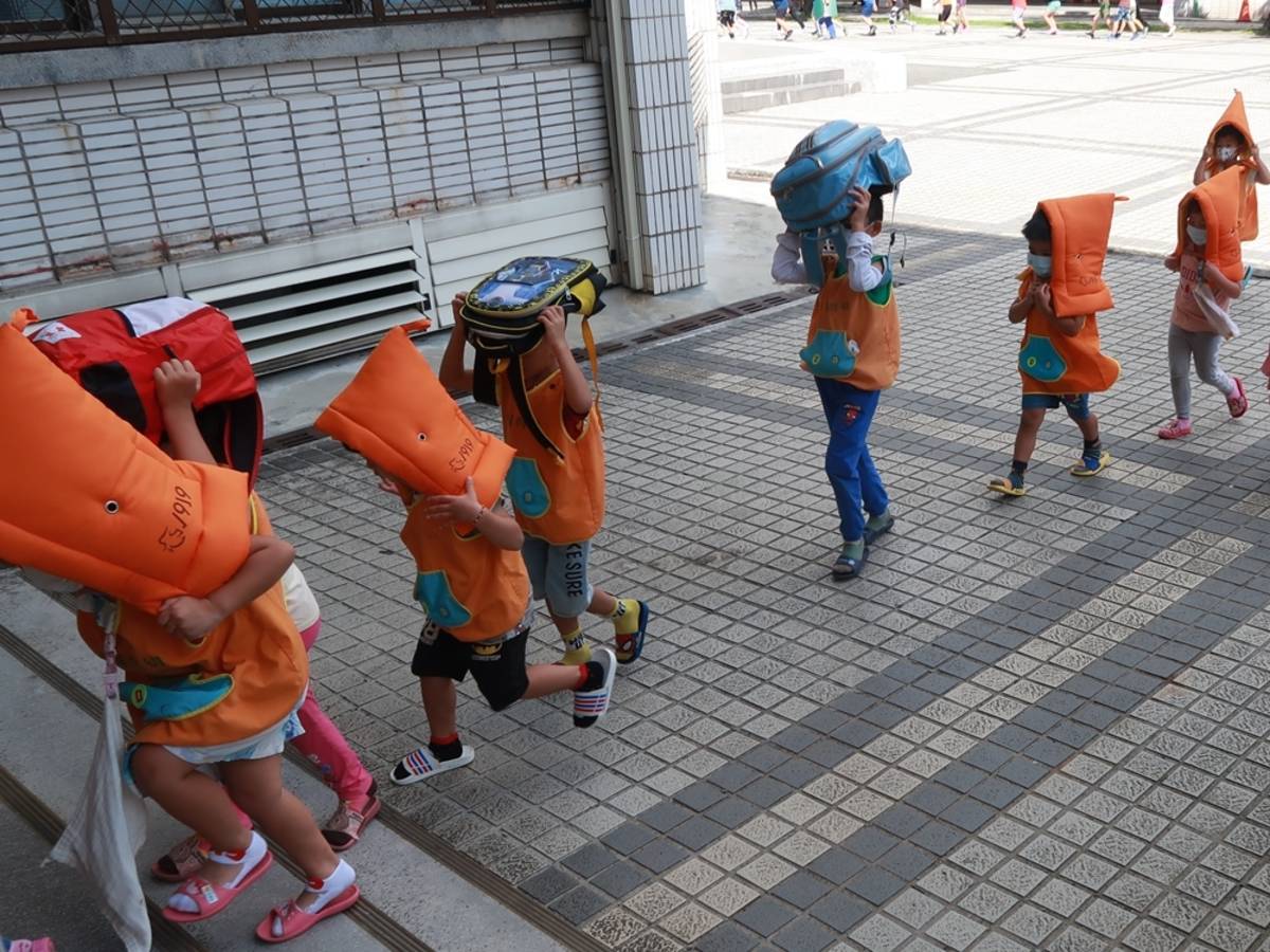 幼兒以頭套或書包保護頭部避難