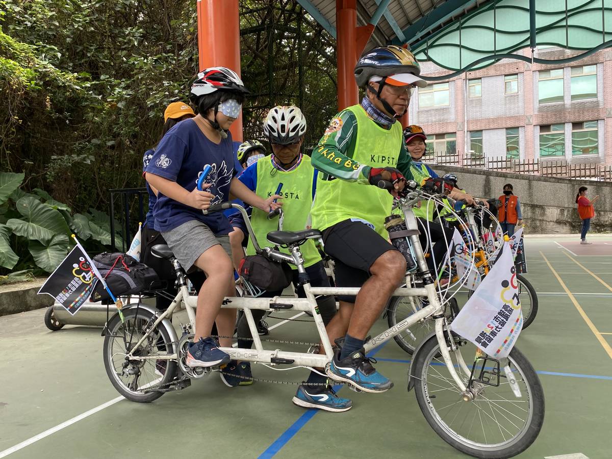 協會志工引導金山國小學生蒙眼實際騎乘協力車體驗視障者騎乘的感受。