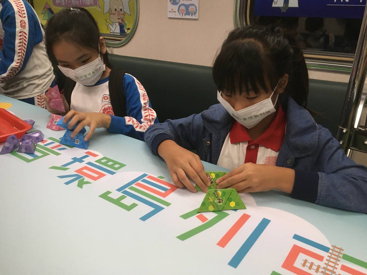 國小學童在師大附中科學班高二學生的引導下，嘗試將不同形狀的紙模型組合成像粽子一樣的正四面體。