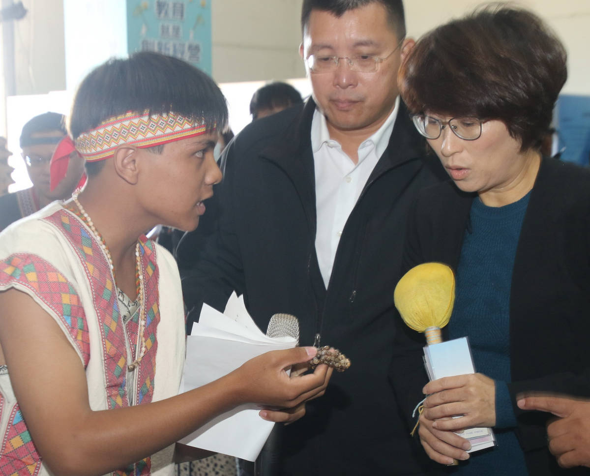 桃源國中胡佳安同學為饒縣長解說，布農族用玉苡珠和菖蒲做成的項鍊能夠避邪和祈福，教育處長林政宏(中)也陪同仔細聆聽。