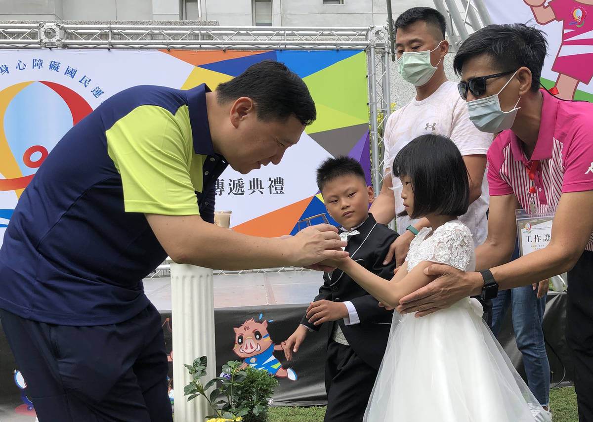 臺東縣副縣長王志輝彎下身，輕柔的從特教生手中接下希望之火。