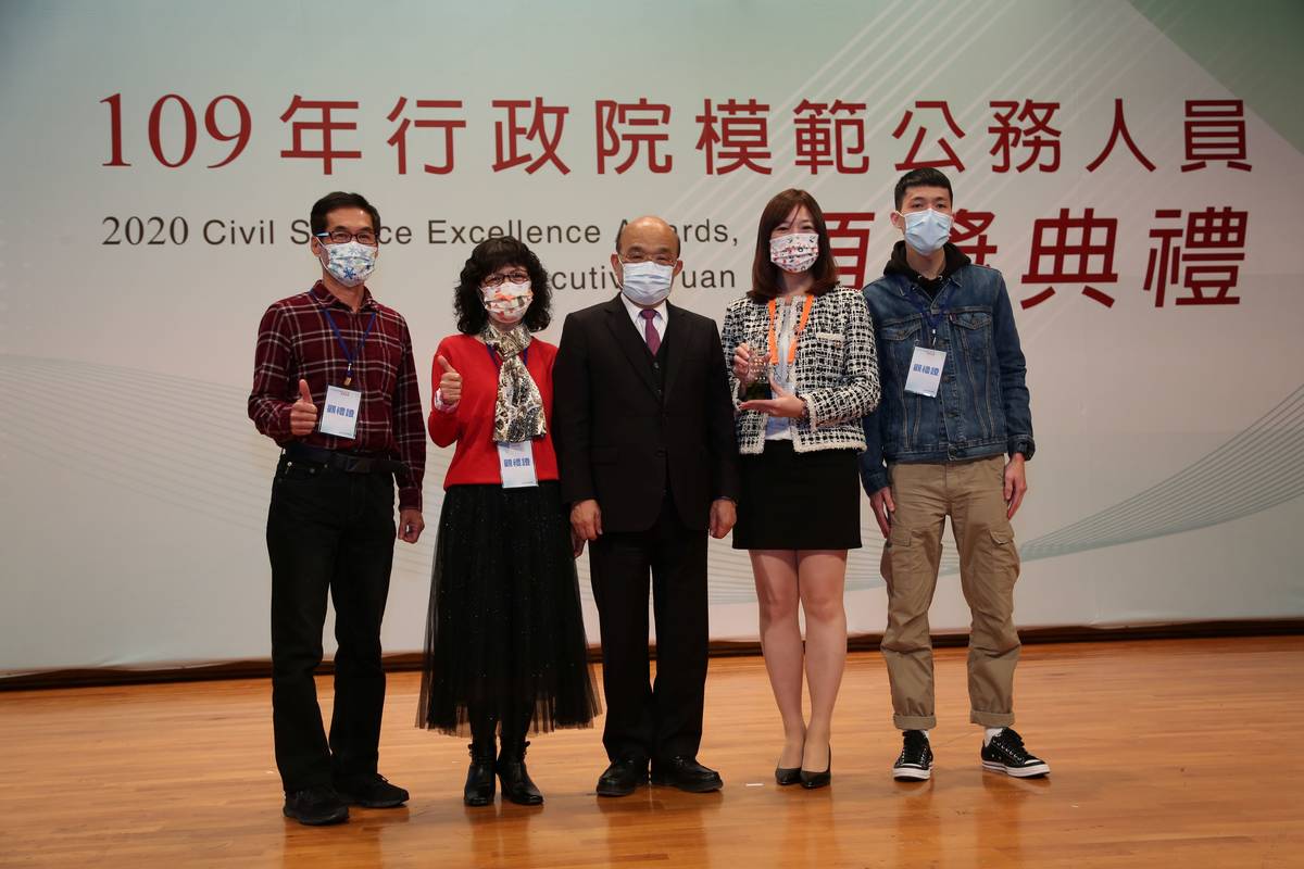 倪嘉伶(右二)獲行政院模範公務員獎，父母、弟弟一同上台合影(行政院人事總處提供)。