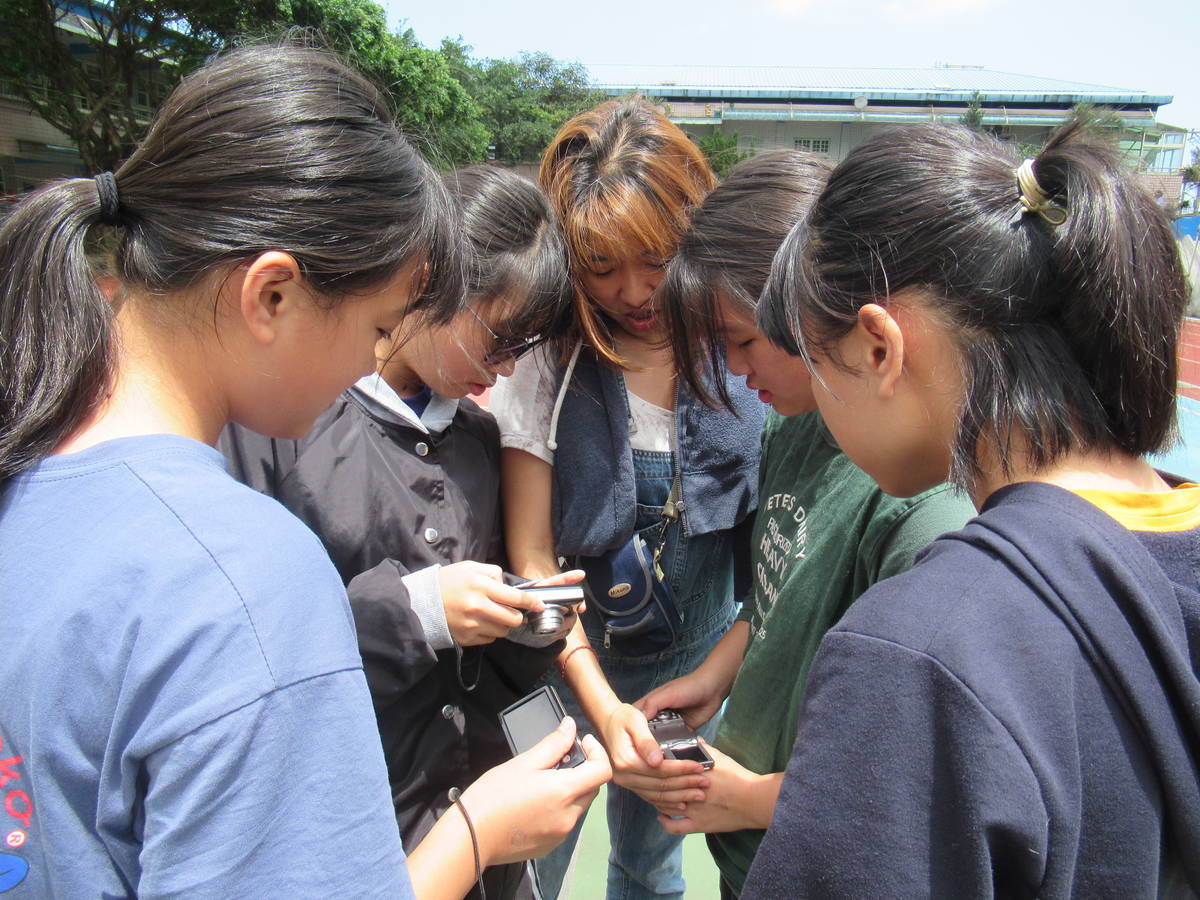 瑞濱國小學生與攝影志工柚子老師(中)分享拍攝到的主題作品。