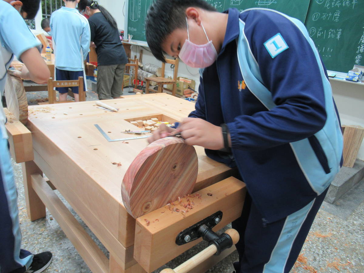 八年級的木工社課製作原木圓凳，學生正將圓凳邊緣的稜角磨得更加平滑。