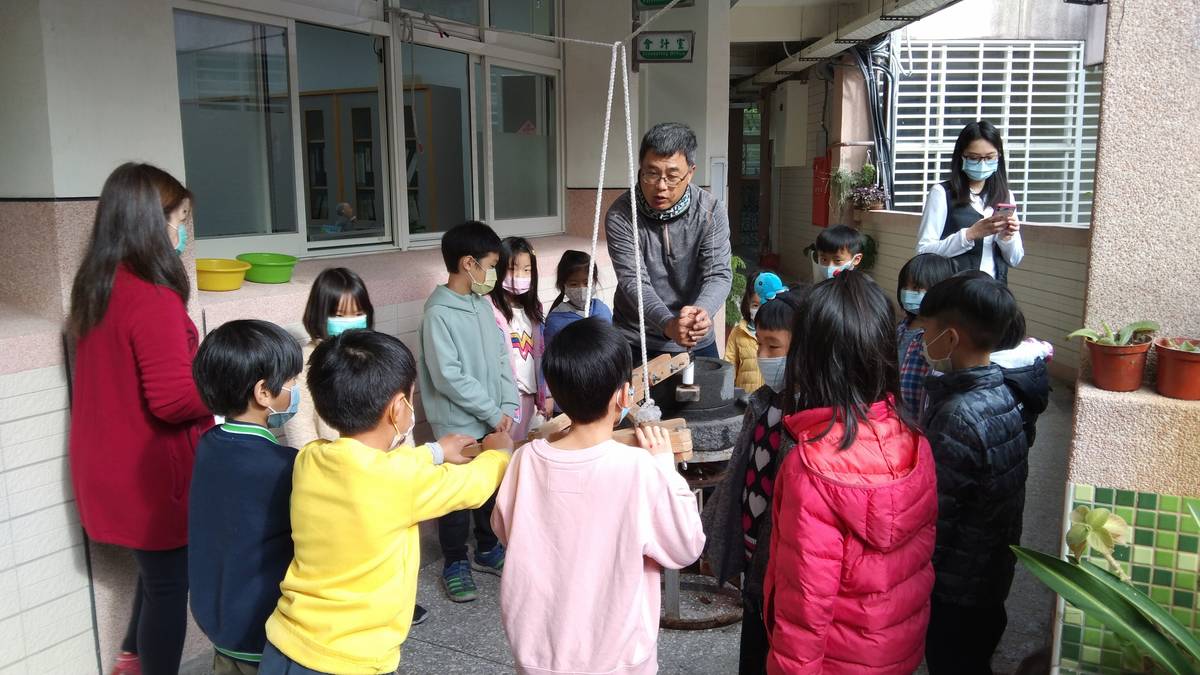 雙溪國小學生將糯米放進石磨磨米漿