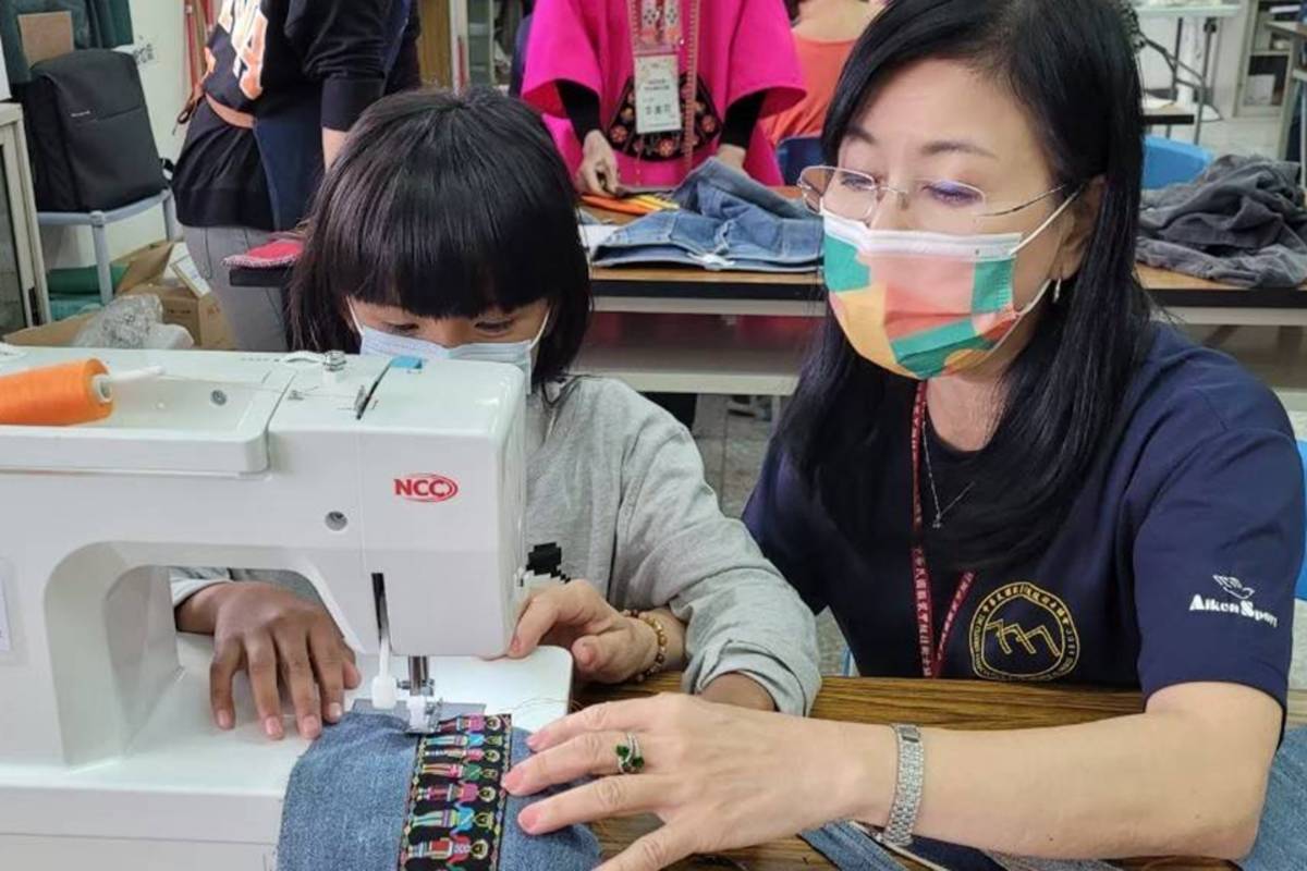 學童在志工指導下使用縫紉機