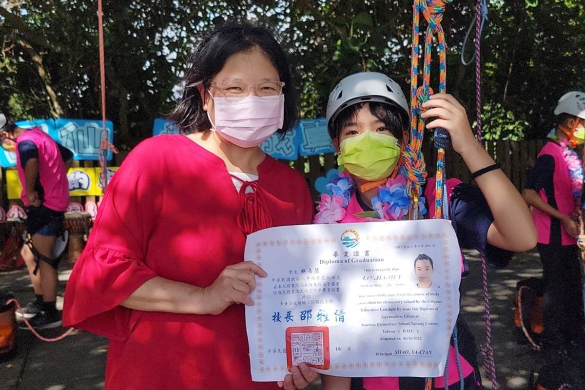 三仙國小校長邵雅倩為畢業生掛上花環祝福攀樹成功。