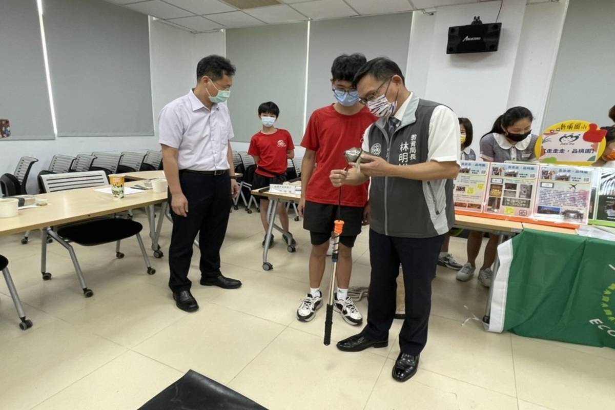 美華國小的陀螺隊享譽全國，教師團隊在今年暑假期間，因應疫情變化，發展出「陀飛碟舞」的特色作業。同學教導林明裕局長陀螺招式 (桃園市教育局提供)
