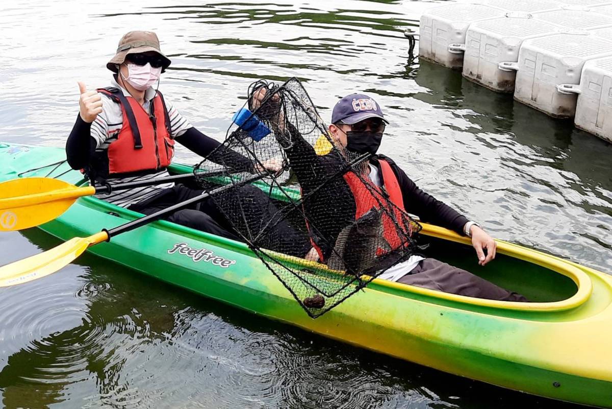 《愛運動˙動無礙》參與學員划獨木舟並靠近浮標，拿取漁網開心展示漁獲(圖片來源:明道大學)