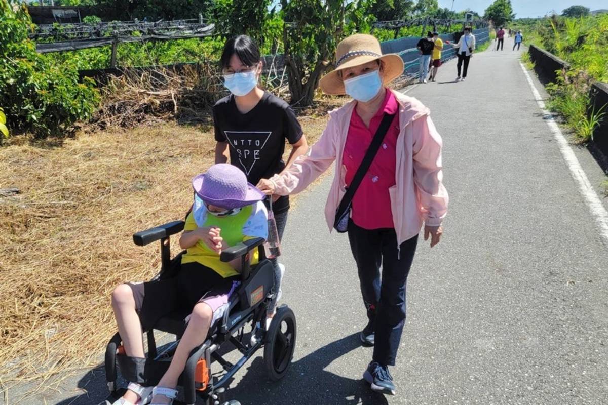 穿著黑色T恤的臺東大學特教系學生，自發擔任身障鐵人賽志工， 協助身心障礙者完成鐵人障礙賽。
