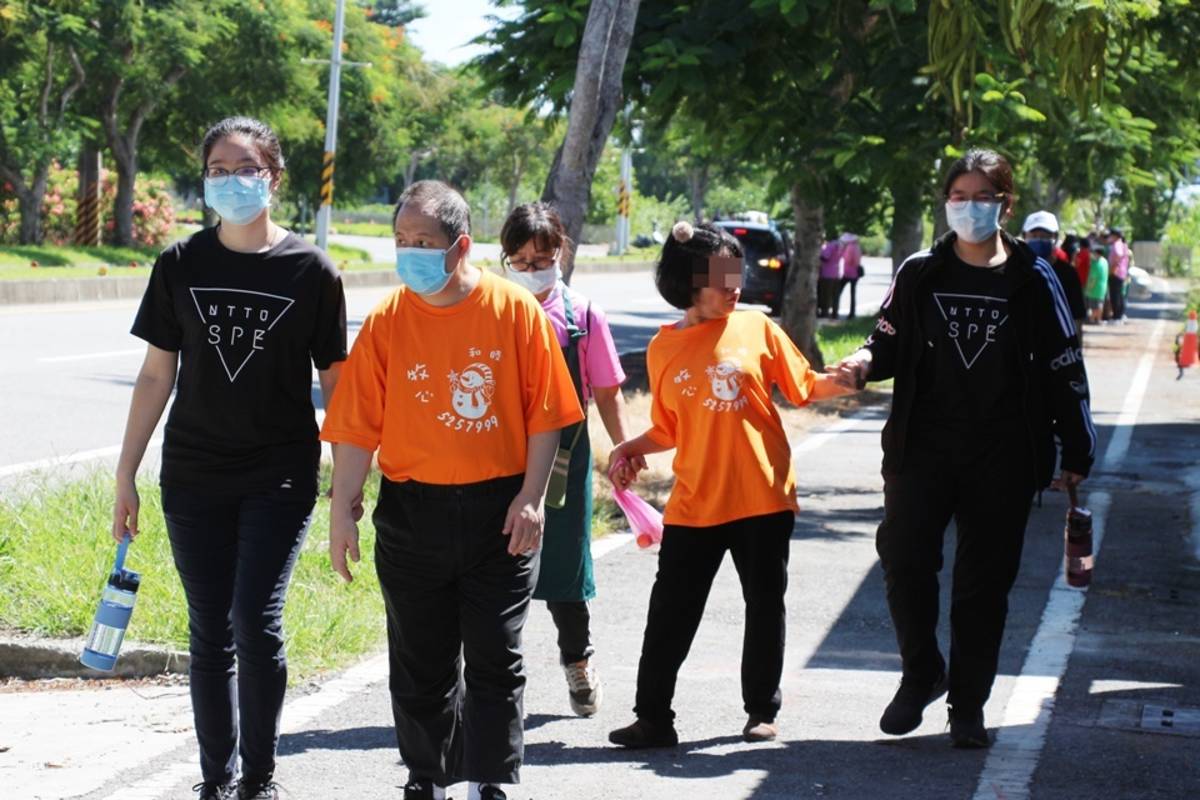 穿著黑色T恤的臺東大學特教系學生，自發擔任身障鐵人賽志工， 協助身心障礙者完成鐵人障礙賽。
