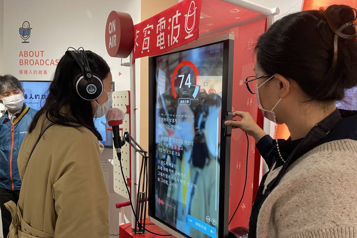 參訪團學者利用教育電臺麥寶電波體驗韓語主播報新聞。