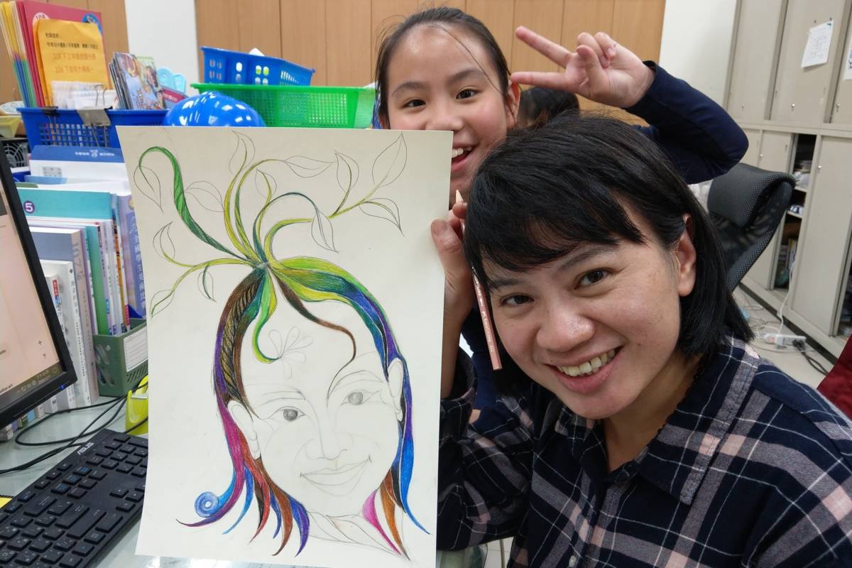 邱曉詩與學生合影，手上拿的是她的自畫像