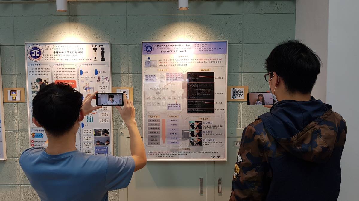 學生正使用手機掃描海報右邊的圖卡，透過AR技術聆聽工管系學生的影片介紹 (元智提供)