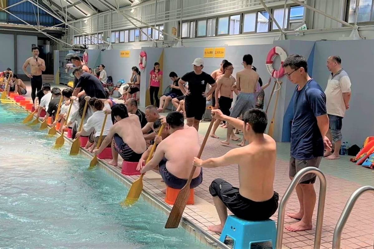 學生在海科大泳池岸邊，透過坐圓板凳模擬坐在龍舟上的情形