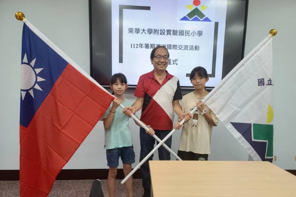鮑明鈞校長將國旗授與魏梓丞（左）、校旗授與陳芝希（右)