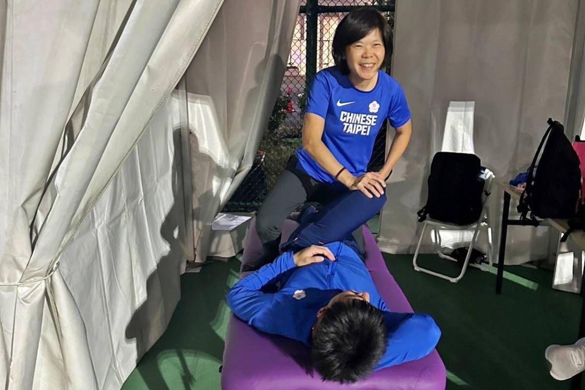弘光科大老師李瑋君(立者)為臺灣最速男楊俊瀚(躺者)進行物理治療。（圖：張凱傑提供）