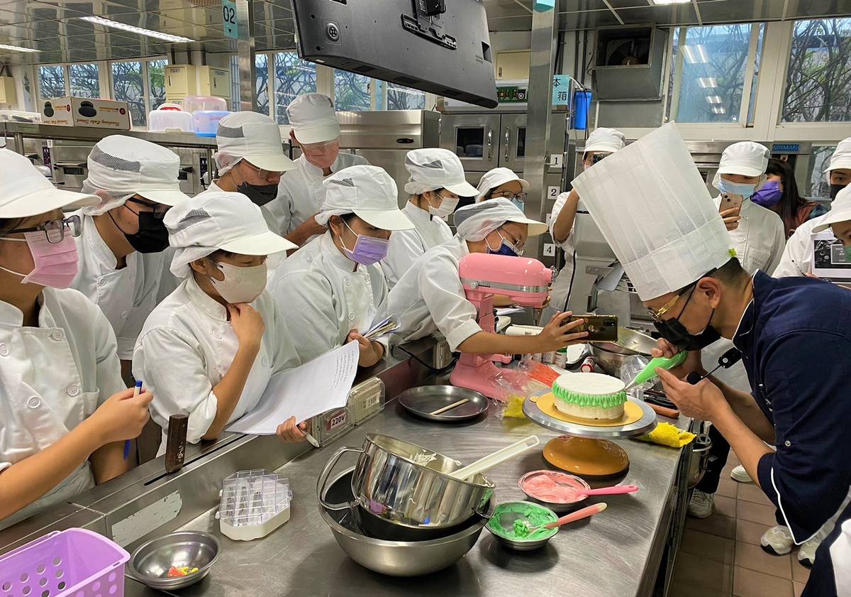 何正雄老師向參與產學合作方案的學生們示範使用不同花嘴「鮮奶油」裝飾蛋糕