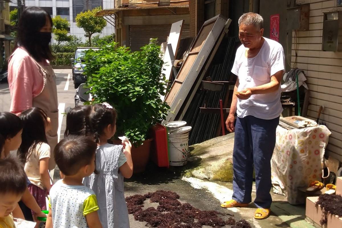 幼兒與當地居民互動，聽爺爺講述曬海藻的故事