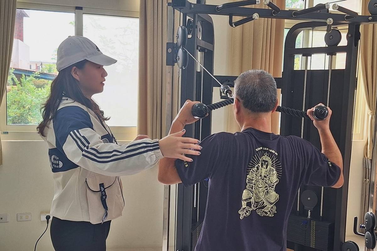 「銀河學院」團隊帶領社區長輩，運用社區中心器材進行肌肉訓練(協助長輩訓練肩外旋)