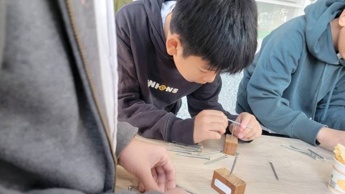 「一釘搞定」，利用兩邊鐵釘重量平衡的原理，讓鐵釘立在直立的鐵釘上