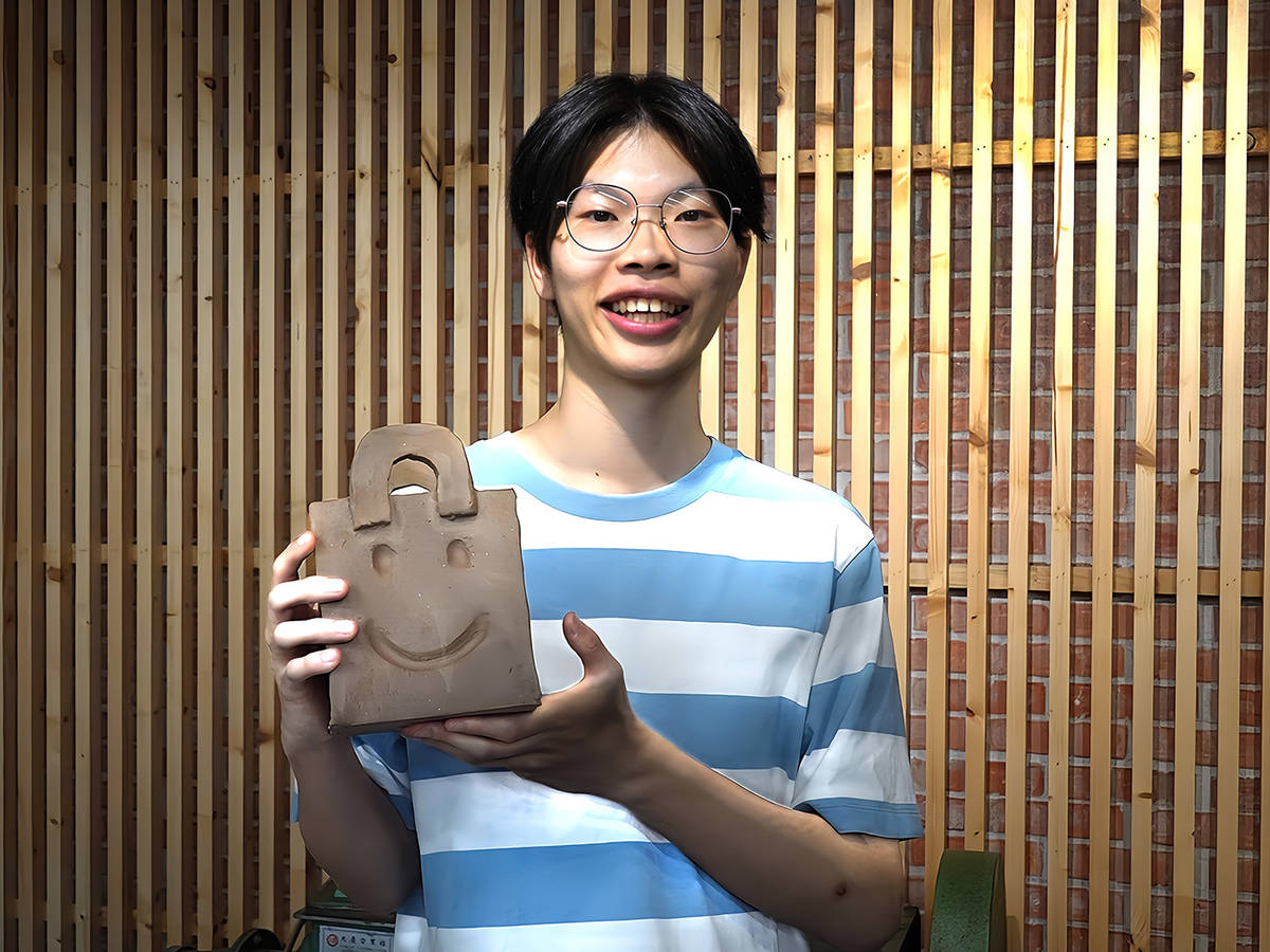 華梵大學智慧生活設計學系學生李翊愷戒除手機成癮，開心展示陶藝作品。(華梵大學提供)