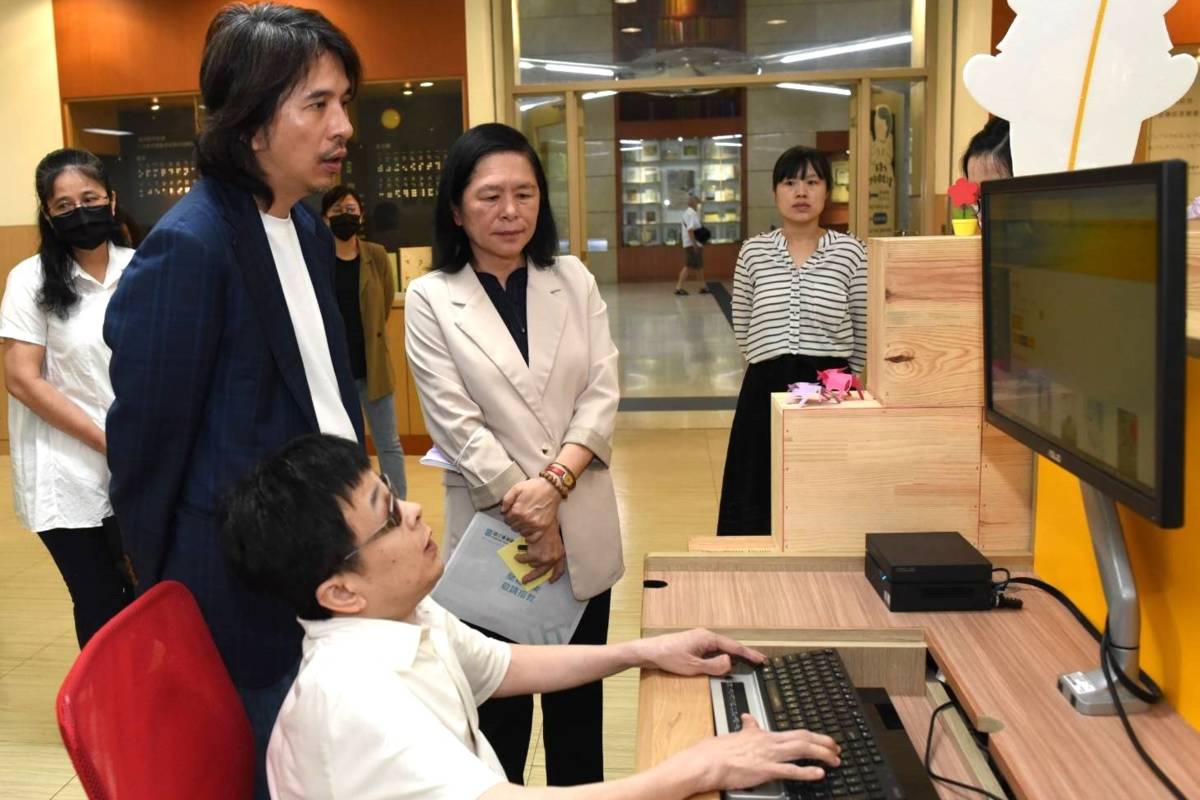 視障館員向葉丙成政務次長(左二)、曹翠英館長(左四)示範無障礙閱讀APP操作步驟。(國臺圖提供)