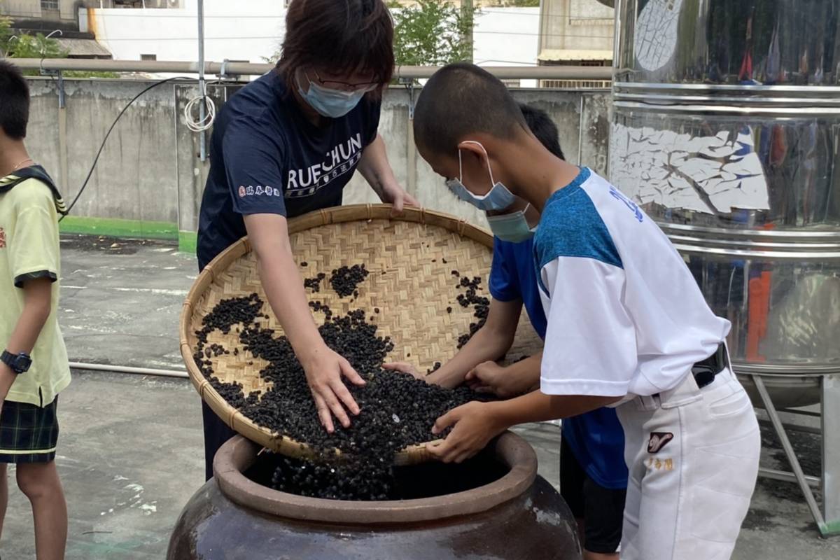 五年級學生將黑豆倒入甕中（圖源：文昌國小）