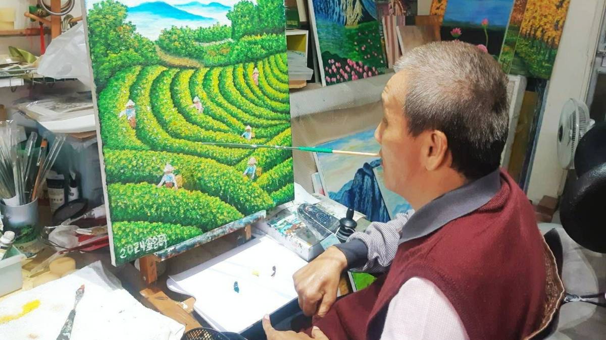 銘哥作畫必須透過口含著筆來創作，相當不容易，但他仍然非常認真的畫。