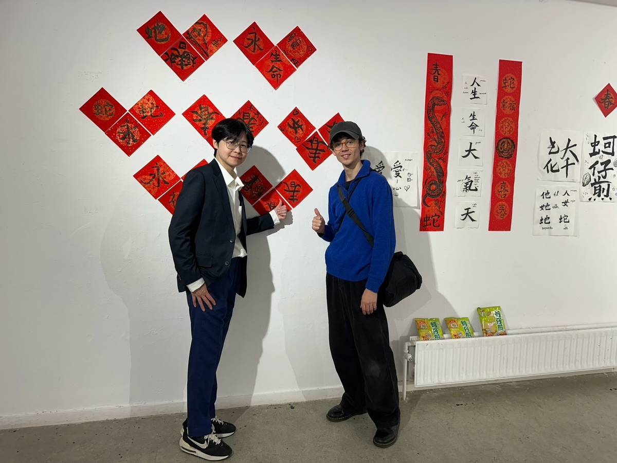 華梵大學教授藝術家楊侖（左）與西班牙學生在書法作品前合影。(華梵大學提供)