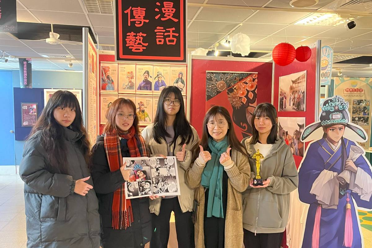 同學與指導老師在展場拿著所繪製的漫畫書合影