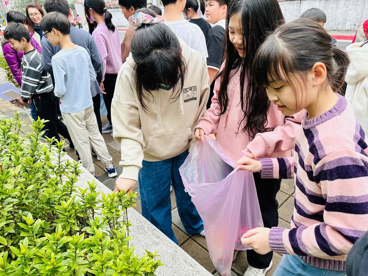 學生用長夾撿拾藏在圍籬花圃中的垃圾