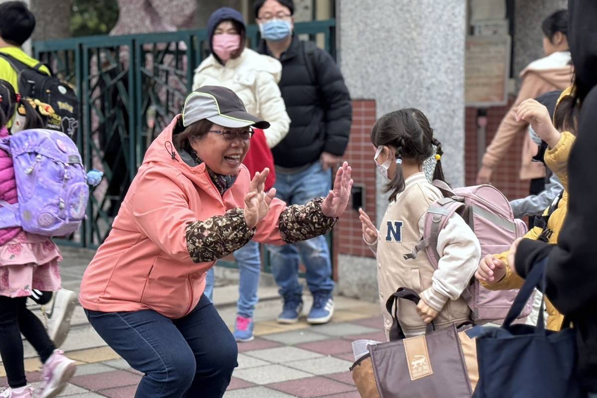 每天早晨，葉瑞珠校長（中）站在校門口迎接學生，張開雙手給孩子最熱情的問候(教育部提供)