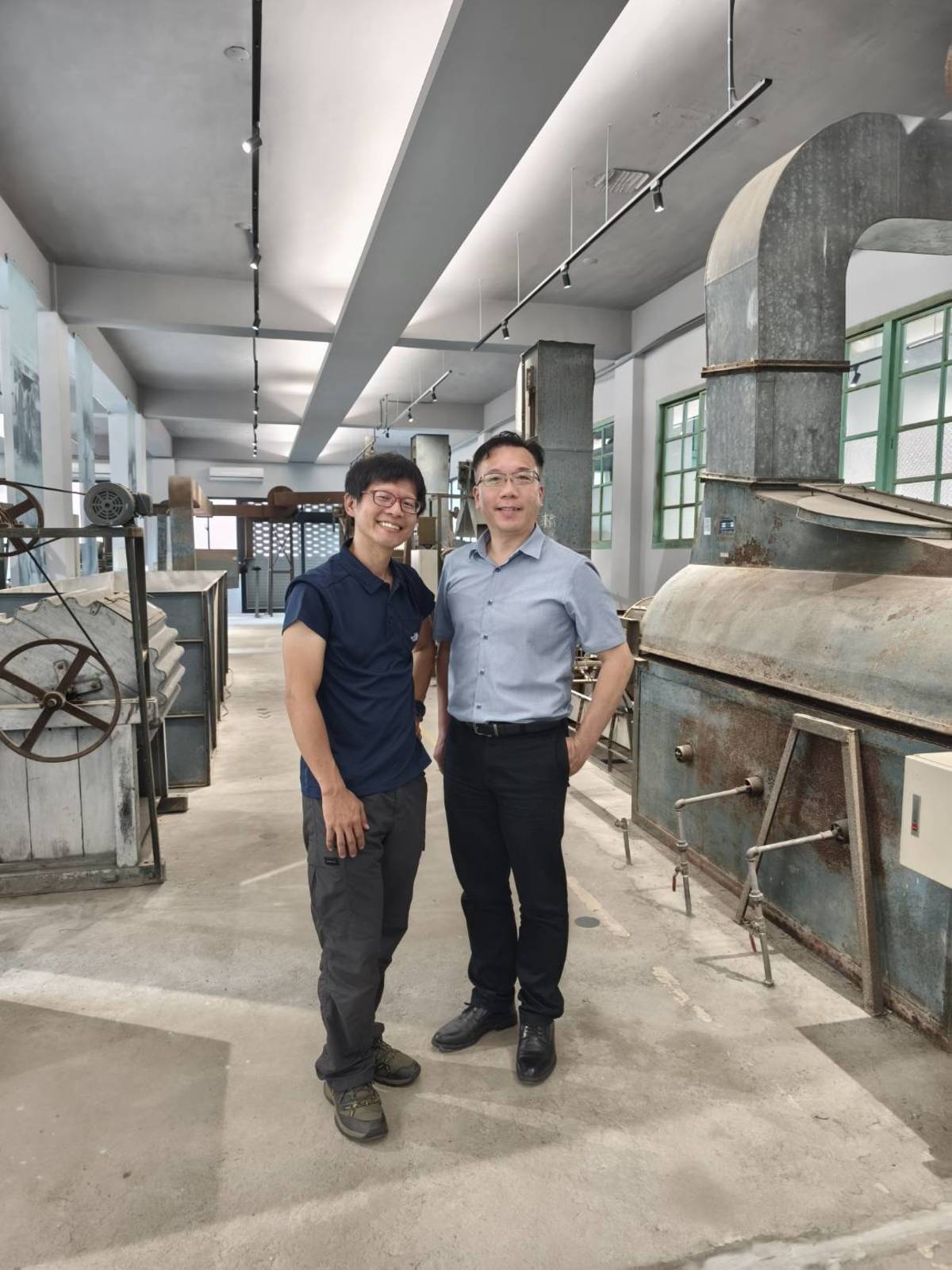 關西高中校長邱宇㨗(右)與實習處主任吳建勳是製茶所改造的重要人物，兩人背後是展示區內的各種機械。