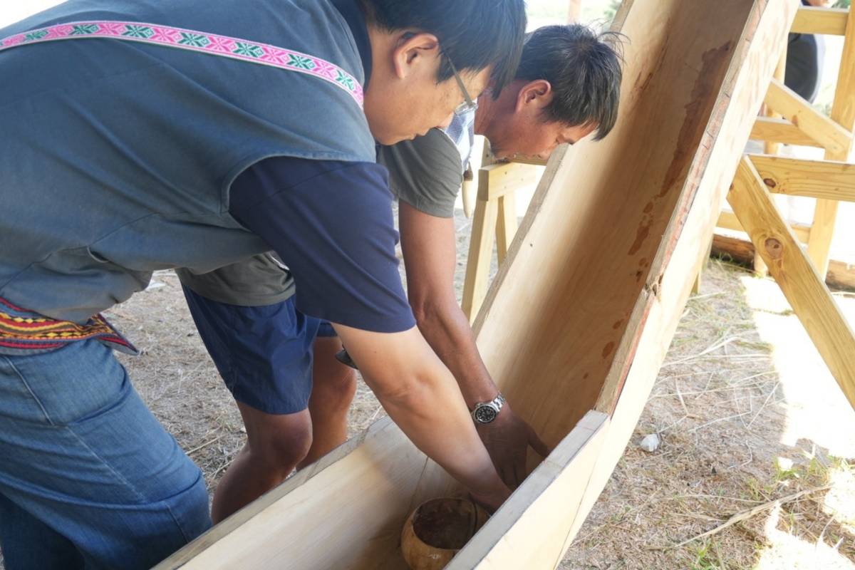 造船學員依循造船師指示，將椰子油塗抹於龍骨與船頭船尾。