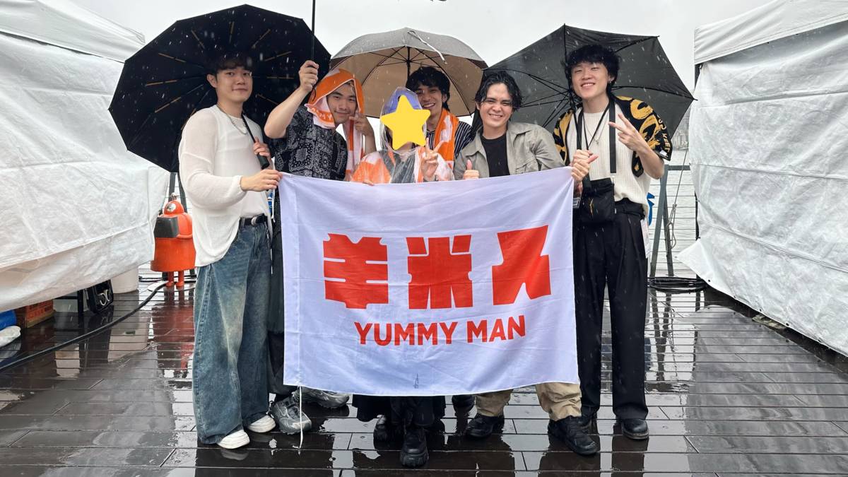 梯梯在2025愛嶼搖滾音樂祭帶著羊米人大旗與樂團合影