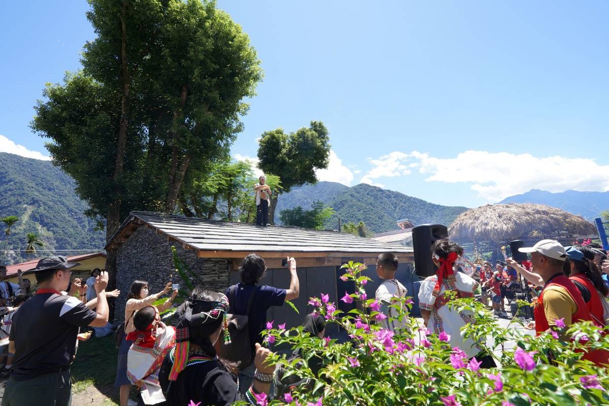 南投縣久美國小感恩祭的主祭者站在家屋屋頂進行拋酒糟儀式。(教育部提供)