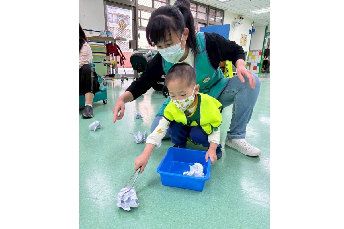 臺北市文山特教學校教師助理朱珮綺引導學生進行夾紙運動